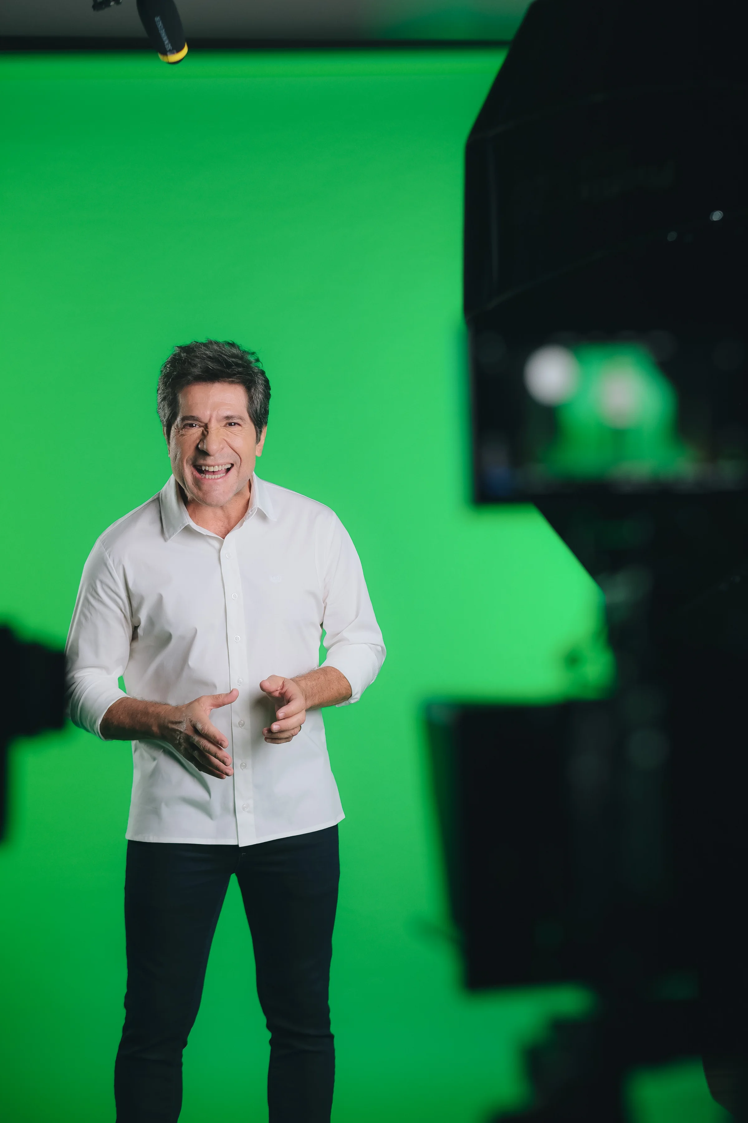 Apresentador fotografado diante de fundo chroma verde no estúdio.